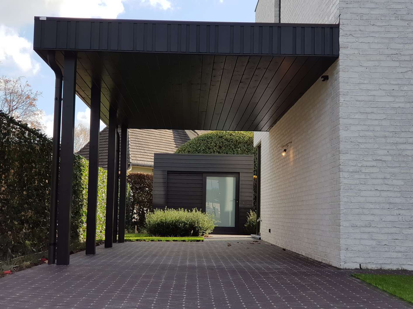 Moderne carport zwart aan gevel bijpassend met tuinberging voor klant uit Oost Vlaanderen