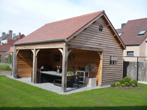 Rustiek bijgebouw in hout met rieten dak en overkapping terras door De Meyer Sleidinge